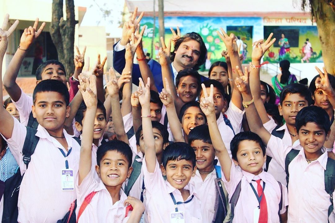 Santosh Talaghatti celebrating with cheering schoolchildren during a rural school visit in India